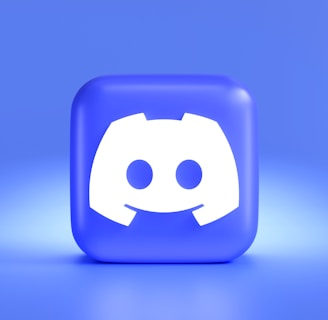 A three-dimensional blue cube featuring a white, stylized gaming controller symbol associated with a popular communication platform, set against a gradient blue background.