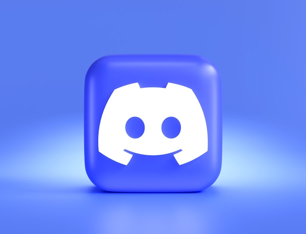 A three-dimensional blue cube featuring a white, stylized gaming controller symbol associated with a popular communication platform, set against a gradient blue background.
